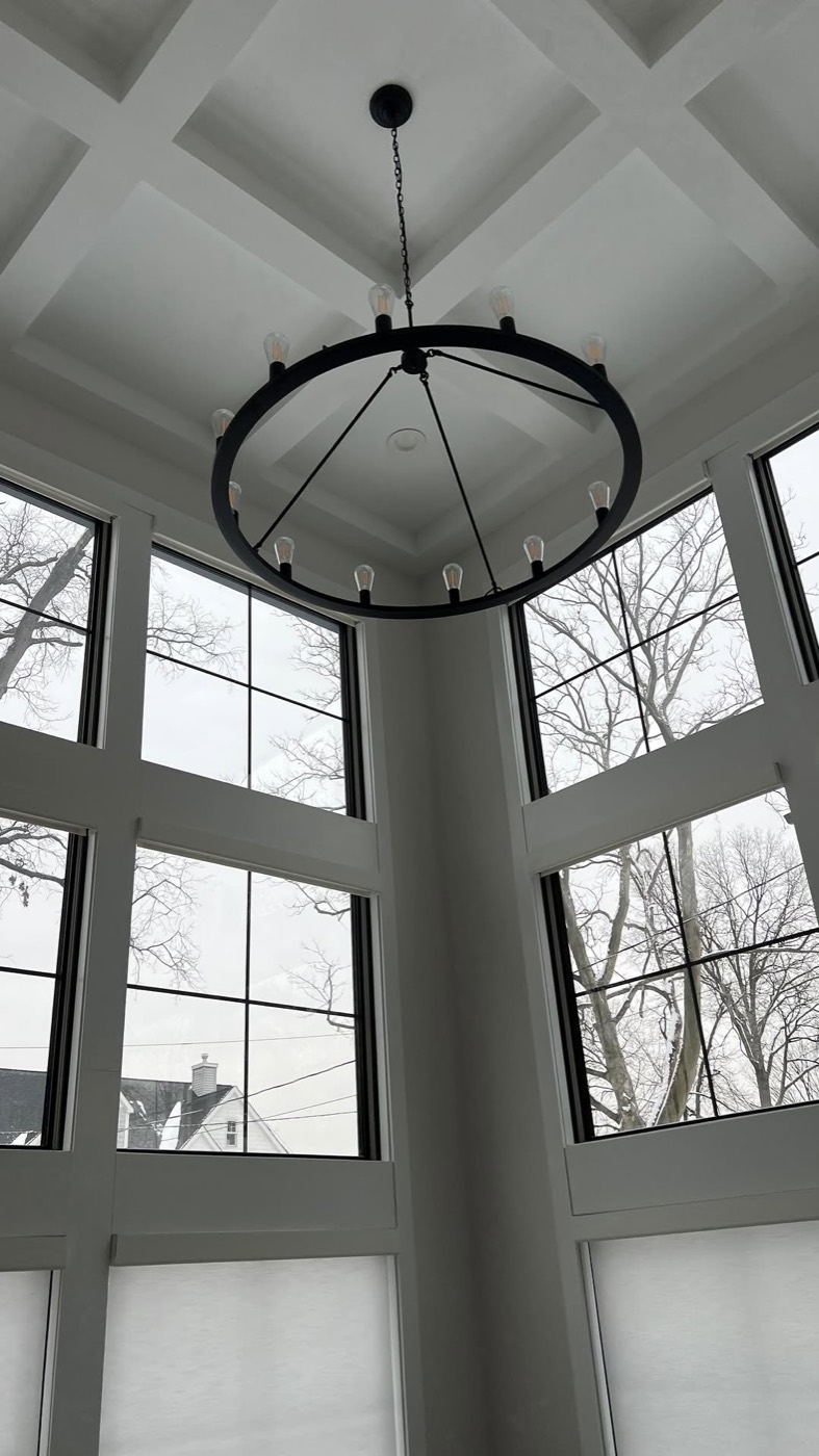 Two-story window wall with finished trim and chandelier